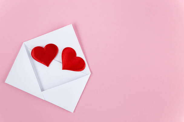 rode harten morsen uit een witte papieren envelop - Foto, afbeelding