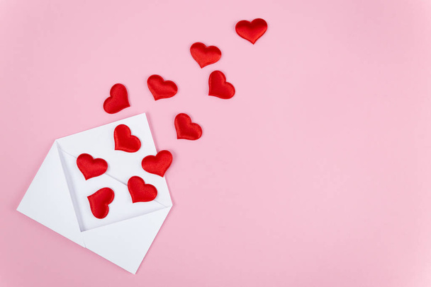 red hearts spill out of a white paper envelope - Fotoğraf, Görsel