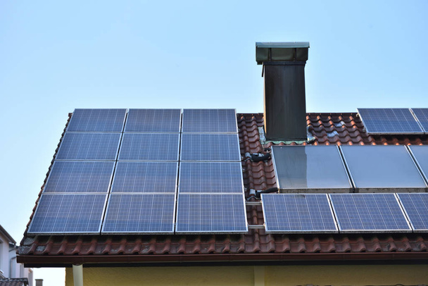 Pannelli solari installati sul tetto di una casa con piastrelle in Europa sullo sfondo di un cielo blu
. - Foto, immagini