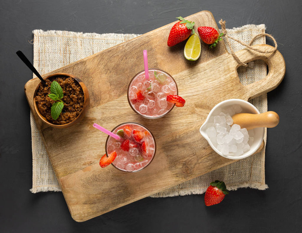Φράουλα Caipirinha, lime, φρέσκο δυόσμο, καφέ ζάχαρη και θρυμματισμένο πάγο. Αεροφωτογραφία - Φωτογραφία, εικόνα