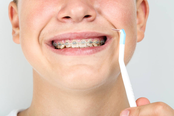 Νεαρός με οδοντόβουρτσα σε γκρι φόντο - Φωτογραφία, εικόνα