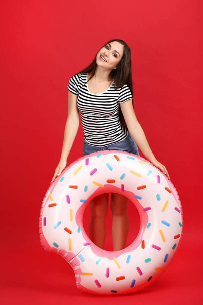 Young girl with inflatable donut on red background - Foto, afbeelding