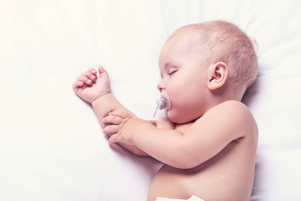 Beautiful little boy with soother sleeping on bed at home - Fotoğraf, Görsel