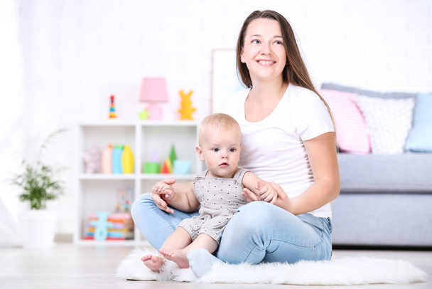 Young mother with baby boy sitting on white carpet at home - Foto, Bild