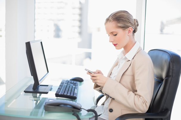 Focused blonde businesswoman text messaging - Fotó, kép