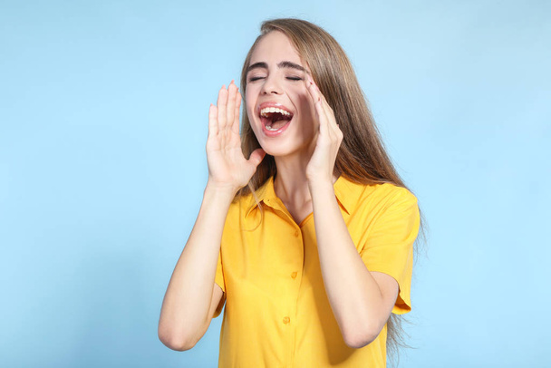 Young beautiful girl screaming on blue background - Foto, Imagem