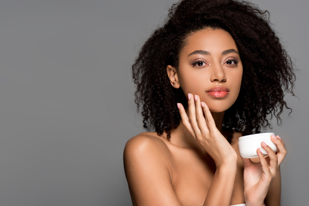 naked african american girl applying face cream, isolated on grey - Fotografie, Obrázek
