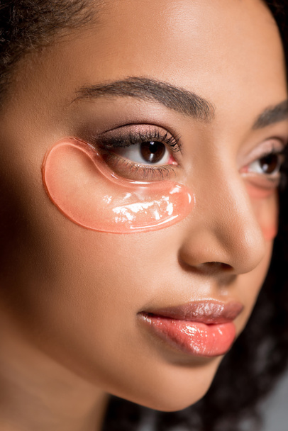 beautiful african american girl with hydrogel eye patches, on grey - 写真・画像