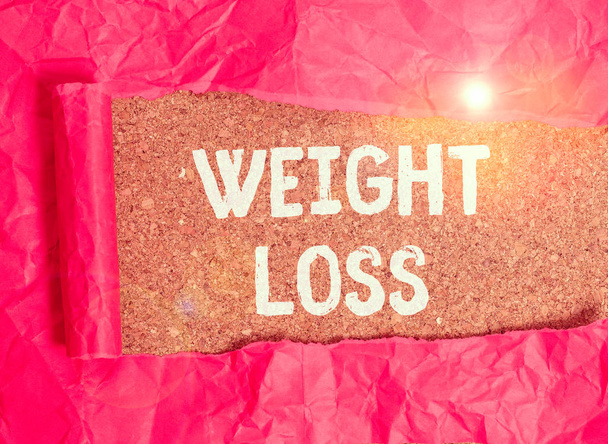 Handwriting text Weight Loss. Conceptual photo the fact of a demonstrating or animals body weight becoming less Cardboard which is torn in the middle placed above a wooden classic table - Photo, Image