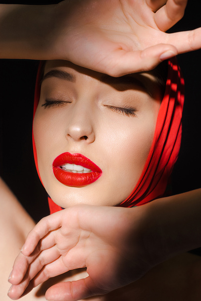 portrait of beautiful elegant girl with closed eyes in red scarf, isolated on black - Фото, зображення