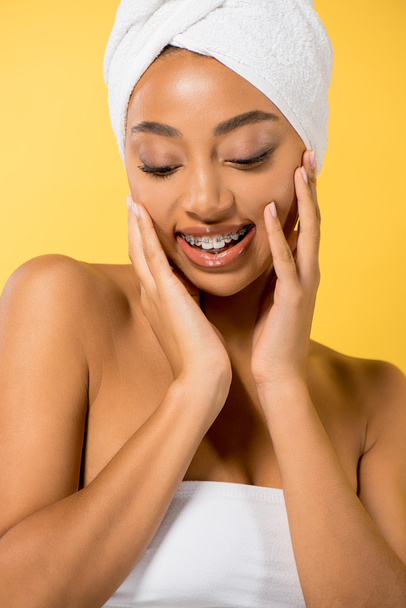 alegre afroamericana chica con frenos en los dientes, aislado en amarillo
 - Foto, Imagen