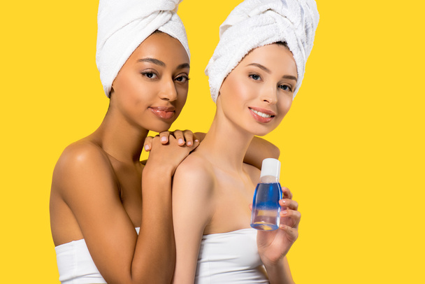beautiful multiracial girls holding makeup remover, isolated on yellow  - Photo, Image