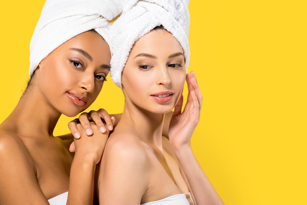portrait of tender multiethnic girls with towels on heads, isolated on yellow - 写真・画像