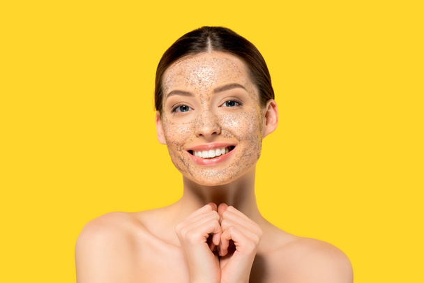 portrait of cheerful naked girl with peeling mask, isolated on yellow - 写真・画像