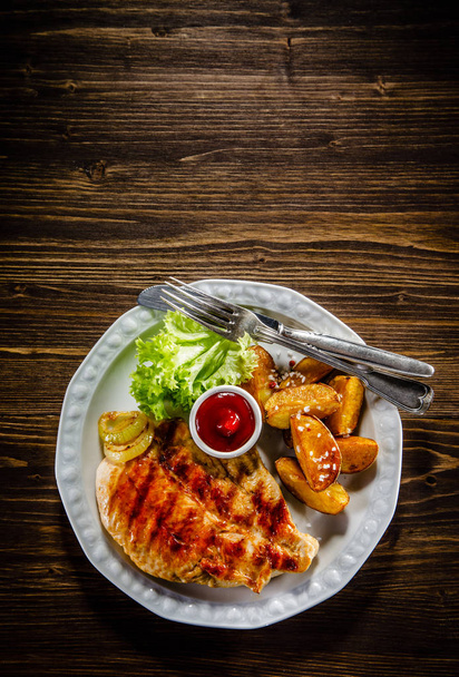 Grilled chicken breast with fried potatoes and bbq sauce. - Foto, Bild