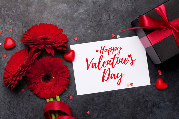 Carte de voeux de Saint Valentin avec bouquet de fleurs de gerbera et boîte cadeau sur fond de pierre. Vue du dessus plat lay
 - Photo, image