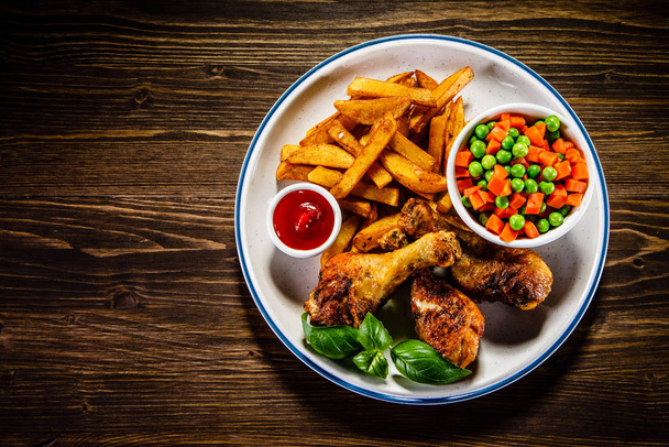 Baked chicken drumsticks with vegetables and french fries with bbq sauce - Fotoğraf, Görsel