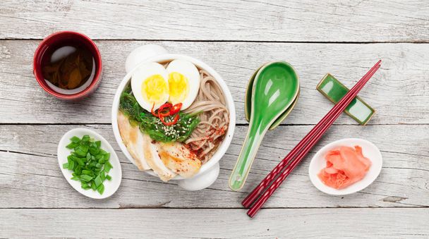 木製のテーブルの上に鶏、野菜、卵とハーブティーとアジア麺ラーメンスープ。最上階平面 - 写真・画像