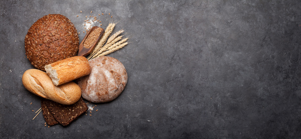 Divers pains avec du blé et de la farine sur table en pierre. Vue du dessus plat avec espace de copie
 - Photo, image