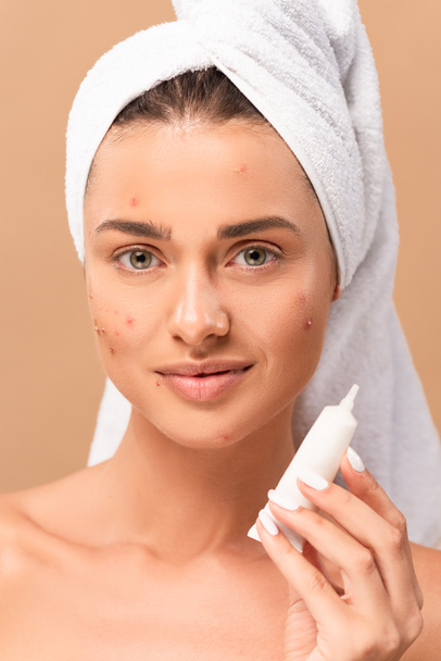 cheerful and naked girl with acne on face holding treatment cream isolated on beige  - Zdjęcie, obraz