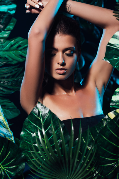 sensual young woman with hands above head near fresh leaves  - Photo, Image