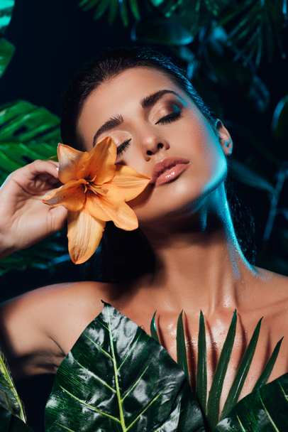 young attractive woman holding orchid near fresh leaves  - Foto, Imagen