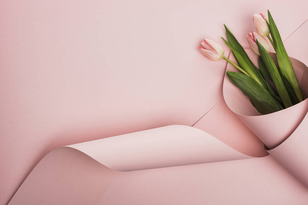 top view of tulips wrapped in paper on pink background - Φωτογραφία, εικόνα