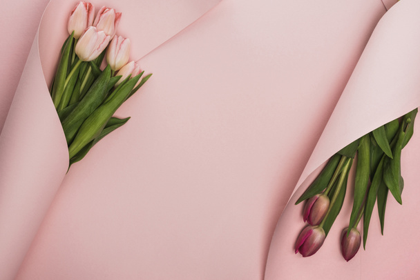 вид сверху розовых и фиолетовых тюльпанов, завернутых в бумажные вихри на розовом фоне
 - Фото, изображение