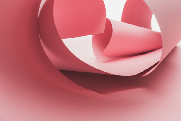 roze papier wervelt met schaduw geïsoleerd op wit - Foto, afbeelding