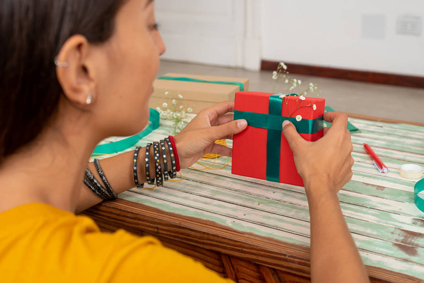 Женщина, упаковывающая подарки ручной работы на стол дома - Фото, изображение
