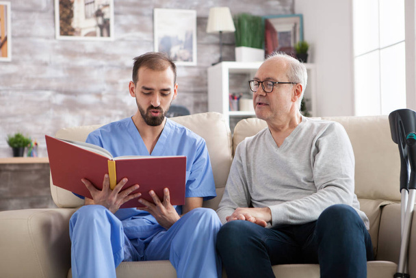Médico masculino lendo um livro para idosos do sexo masculino
 - Foto, Imagem