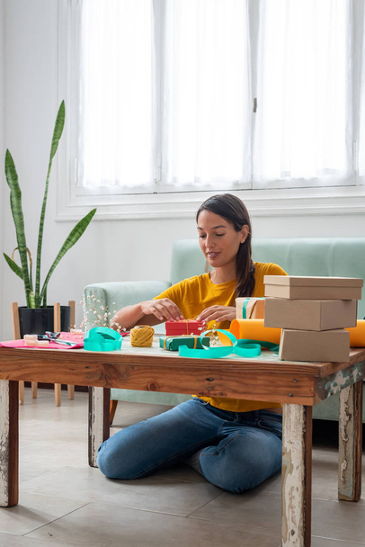Une femme enveloppant des cadeaux artisanaux faits à la main sur la table à la maison - Photo, image
