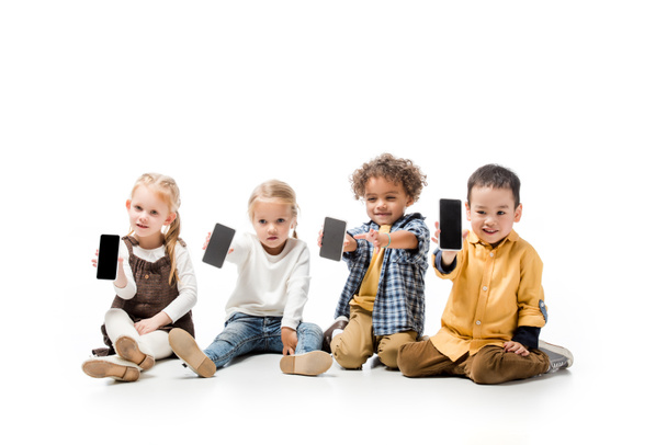 felici bambini multiculturali che mostrano smartphone con schermi vuoti su bianco
 - Foto, immagini