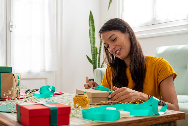 Woman wrapping handmade craft gifts on the table at home - Foto, immagini