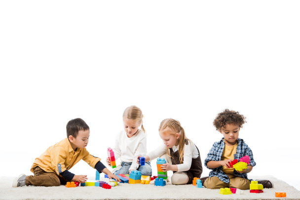 multicultural children playing with wooden blocks on carpet, isolated on white - Zdjęcie, obraz