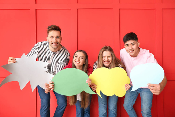 Group of young people with blank speech bubbles on color background - Photo, Image