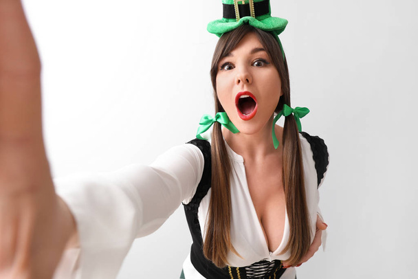 Lustige junge Frau macht Selfie auf hellem Hintergrund. St. Patrick 's Day Feier - Foto, Bild