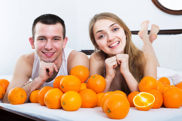 Couple with oranges in bed - Photo, image