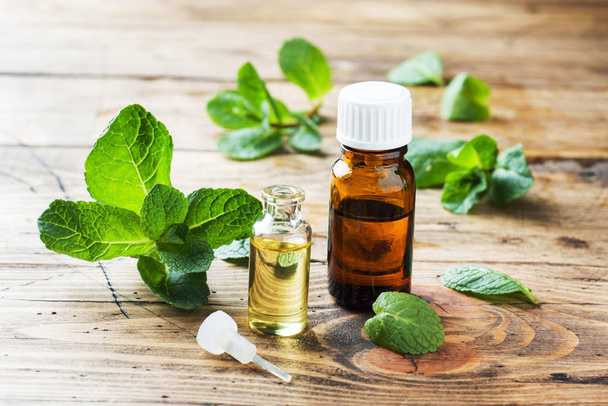 Essential aroma oil with peppermint on wooden background. Selective focus, copy space. - 写真・画像