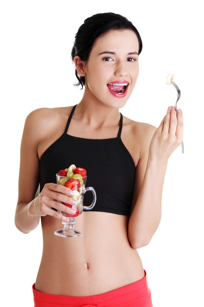 Pretty fit woman eating fruit salad - Zdjęcie, obraz