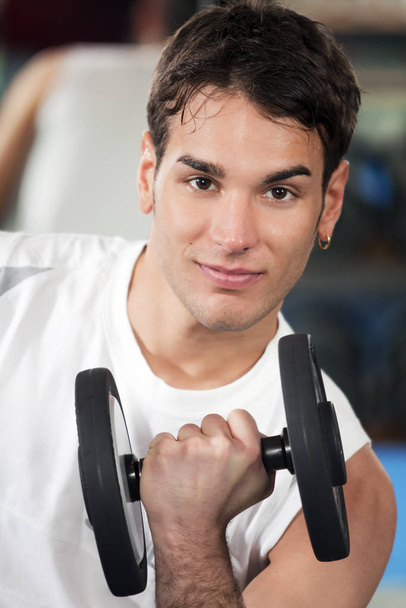 young man doing exercises with dumbbells in gym - 写真・画像