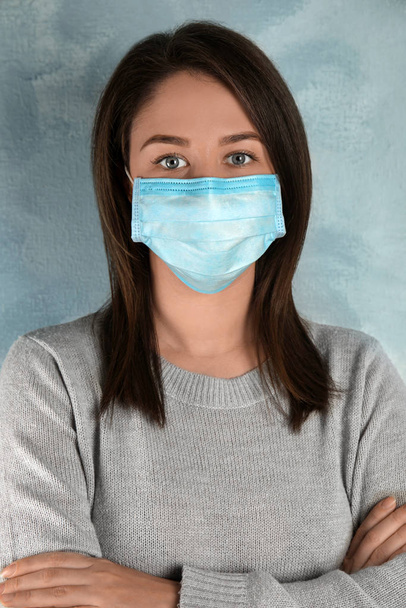 Woman with disposable mask on face against light blue background - Foto, imagen