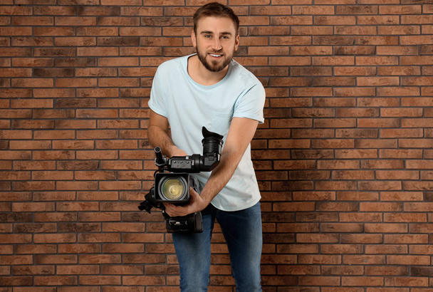Operator with professional video camera near brick wall - Photo, image