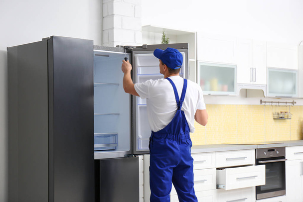Male technician with screwdriver repairing refrigerator in kitch - Fotoğraf, Görsel