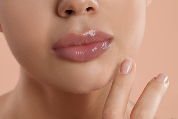 Young woman with beautiful full lips on peach background, closeup - Фото, зображення