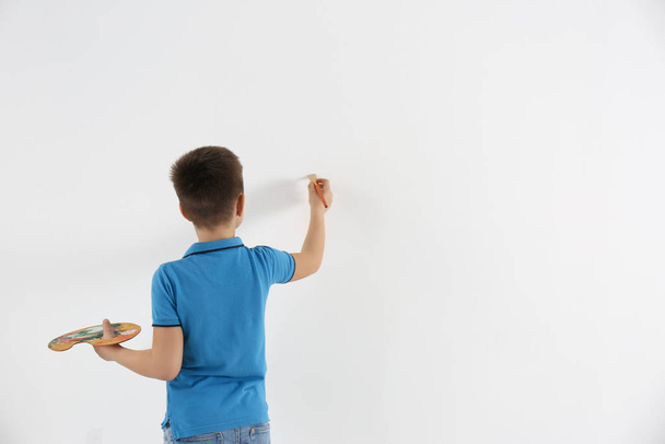 Little child painting on white wall indoors. Space for text - Foto, Bild