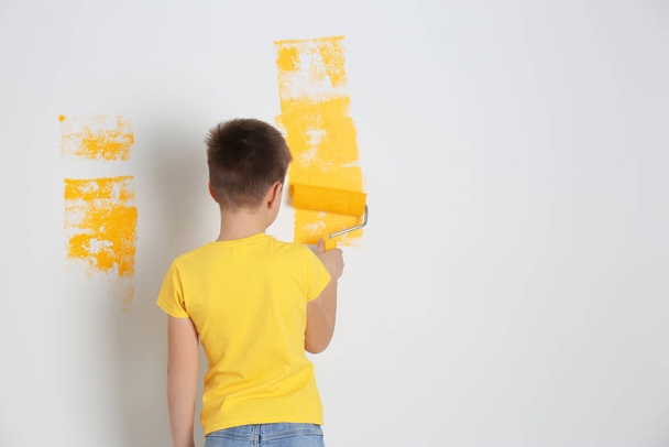 Little child painting wall with roller brush indoors - Foto, immagini