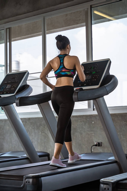 beautiful asian girl is walking on a treadmill in the gym.She Se - Photo, Image