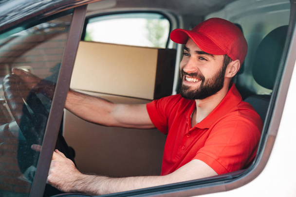 Image of happy young delivery man smiling and driving van - Foto, afbeelding