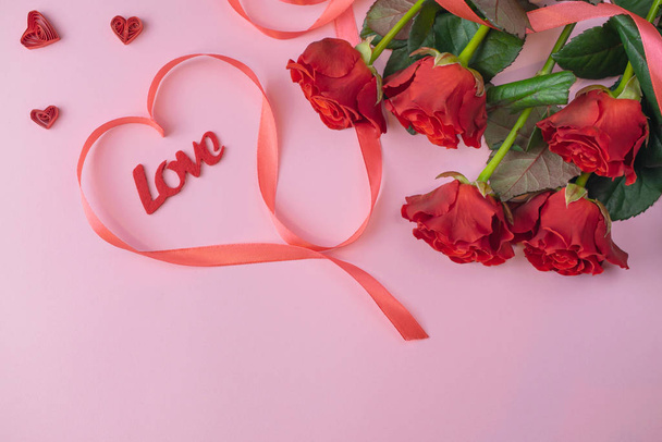 Romantische Saint Valentine roze achtergrond kaart met boeket van prachtige rode rozen en Love belettering - Foto, afbeelding